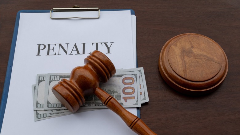 Clipboard that says penalty with money and a gavel on top