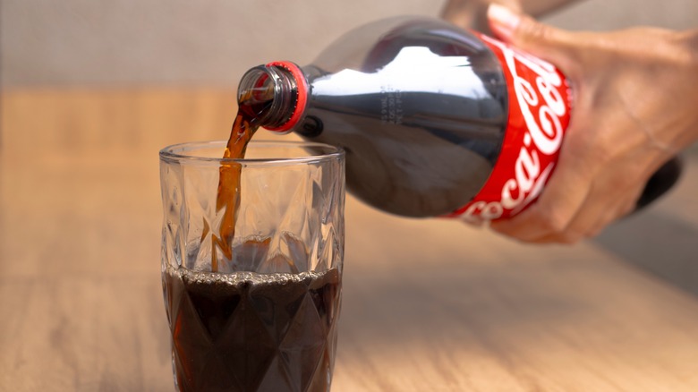 on left woman wearing glasses and red lipstick pinches her nose; on right a can of Coke pours into a glass