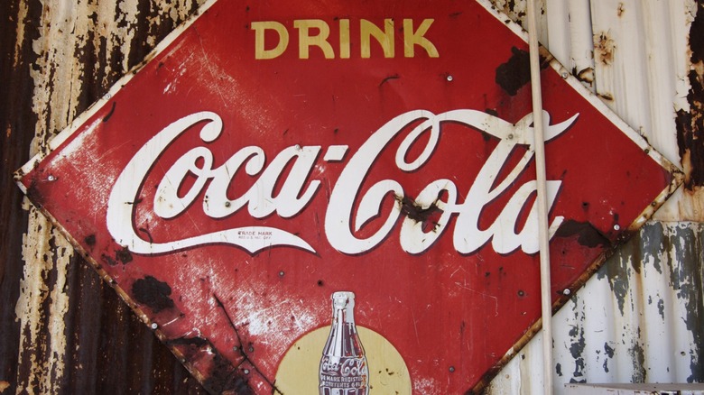 vintage and weathered metal Coca-Cola sign attached to a corrugated metal structure