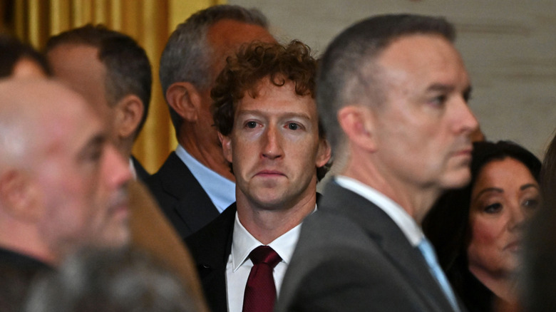 Suited Mark Zuckerberg frowns in a crowd