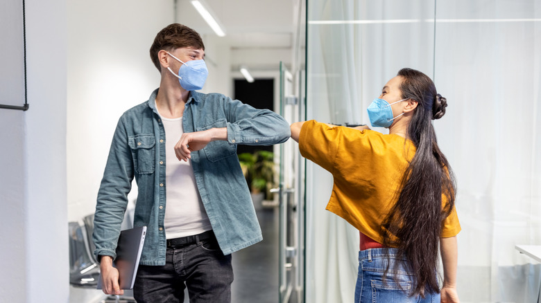 Office workers greeting each other with elbow bump at work