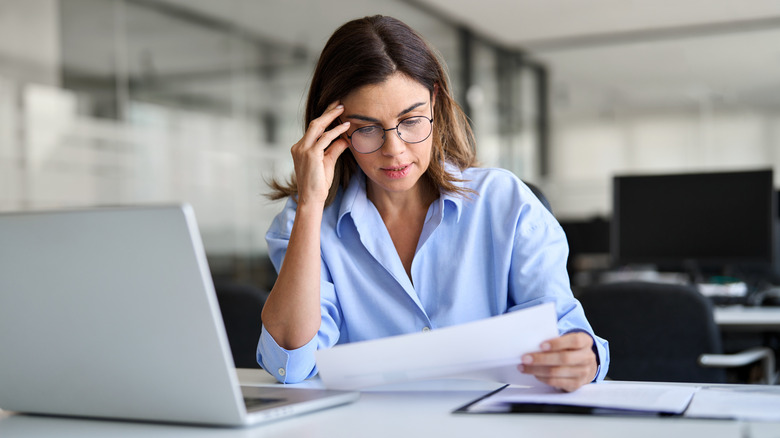 Stressed woman looking at a document at a desk