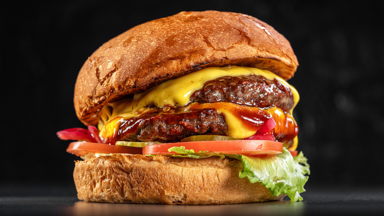 A hefty double cheeseburger against a black background