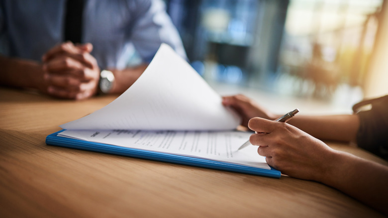 Person signing document on desk.
