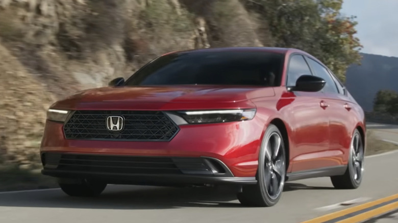 A red 2026 Honda Accord Hybrid Sport rounding a bend on a mountain road