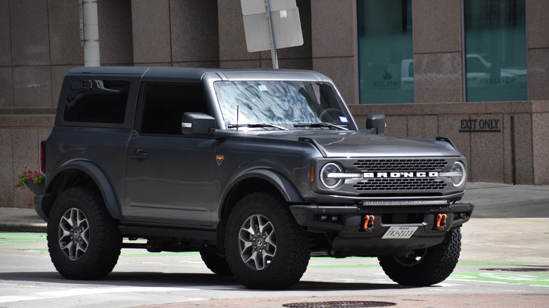 A portrait of a gray Ford Bronco Sport SUV cruising in a downtown district.