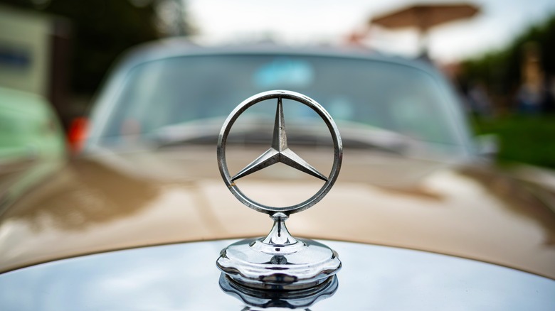 A Mercedes Benz hood ornament on the front of a retro vehicle
