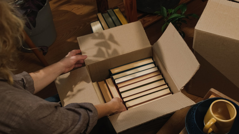 A moving box being packed with books.