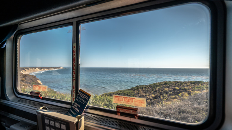 A gorgeous view of the California coast through an Amtrak train window on a blue sunny day