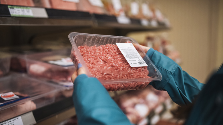 Person holding ground beef package.