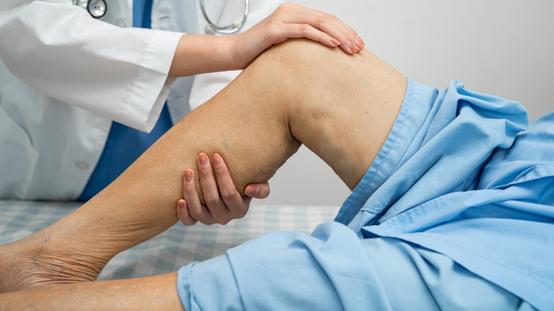 Doctor checking elderly person's knee for surgery