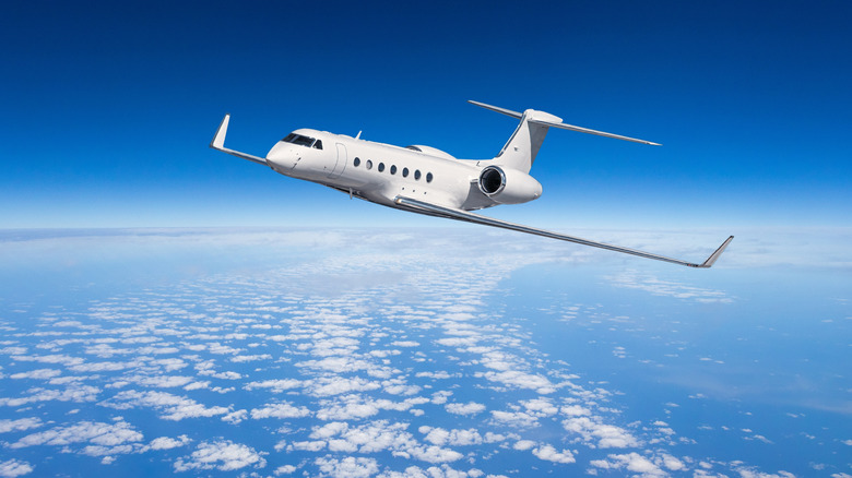Luxury private jet flying over clouds in the sky