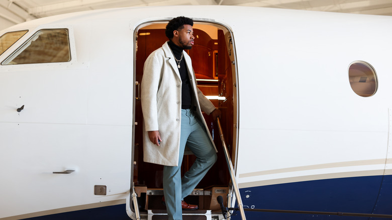 Wealthy individual looking out from the stairs of their private jet
