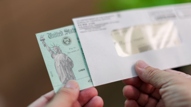 Hands pulling a U.S. Treasury check from an envelope
