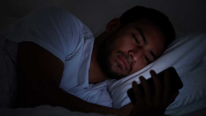 man looking at his phone while in bed
