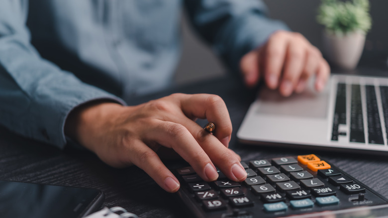 hands of a professional using calculator and laptop