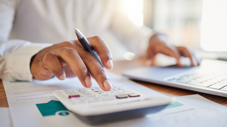 man's hands working with a calculator
