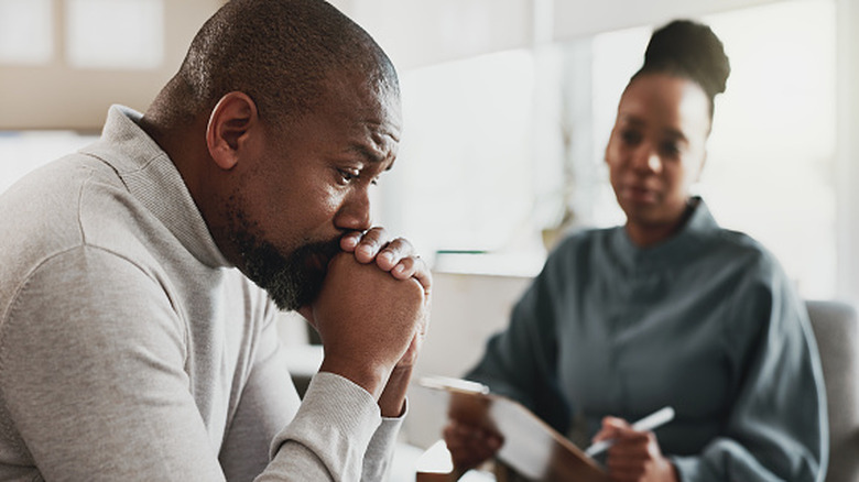 A distressed middle aged man talking to a woman who is taking notes.