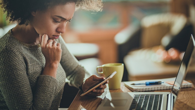 A young woman looking frustratingly at a cell phone as a possible victim of a digital Cash App scam.