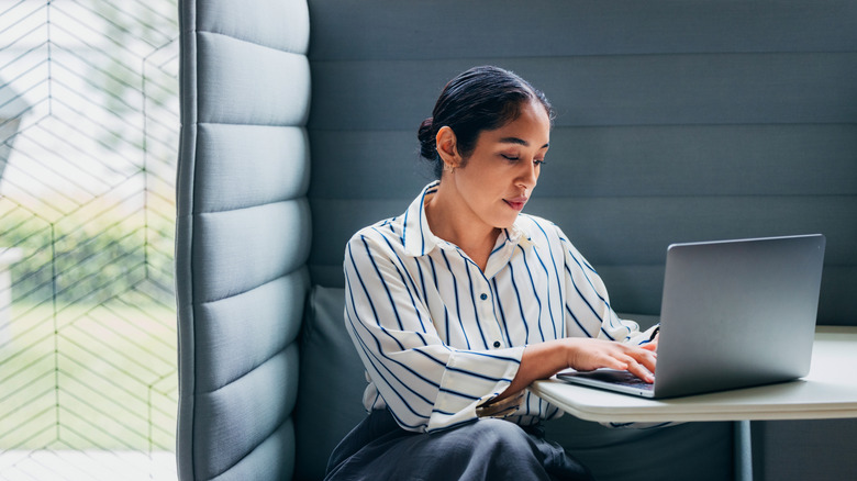 A woman consolidating on a laptop while sitting at table.