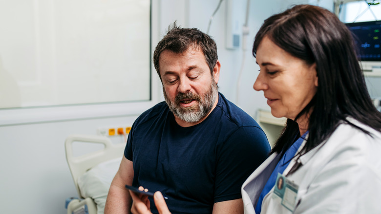 Doctor showing male patient a smartphone app