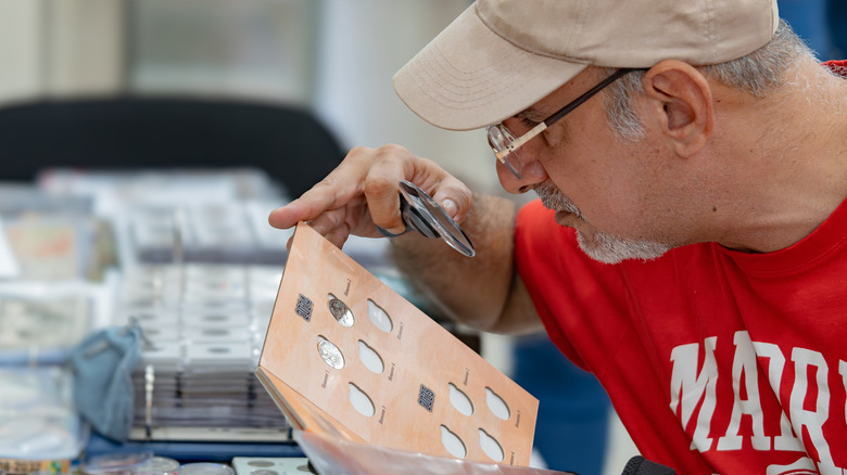 Man looking at coin with magnifying glass