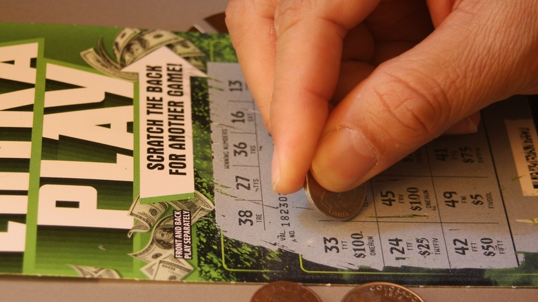 Man's hand scratching off lottery ticket in America