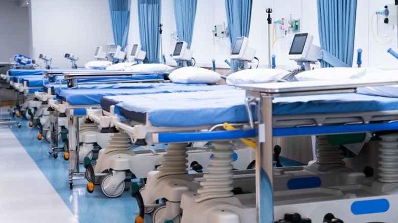 Empty hospital beds lined up in a row in a hospital emergency ward.
