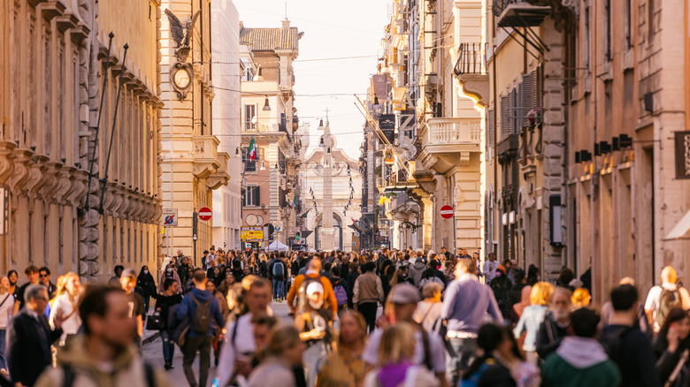 A massive crown of people walking down a street in Europe.
