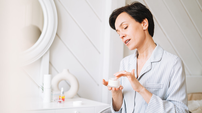 Woman in pajama's applying cream as part of nighttime skin care routine