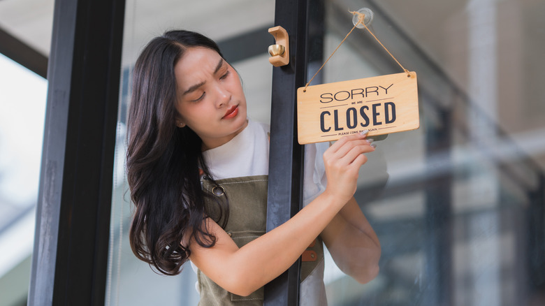 Young woman flipping a closed sign on a store's front door