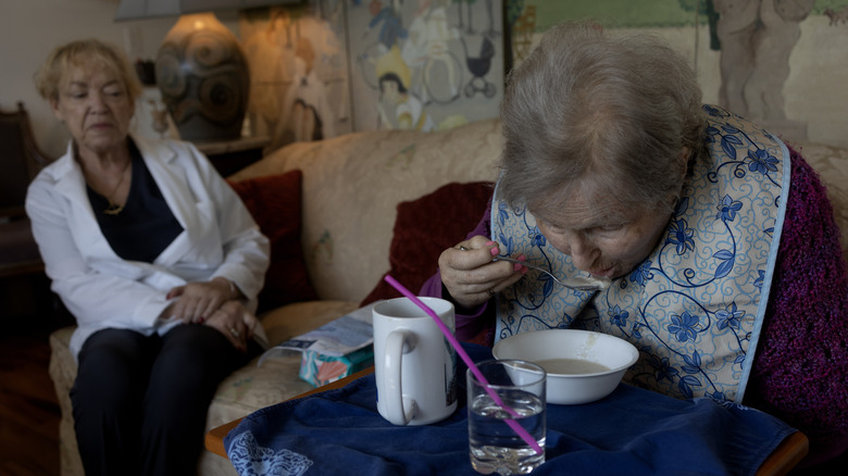 A 90-year-old senior citizen eats while being watched by a health aide in Sarasota, Florida.