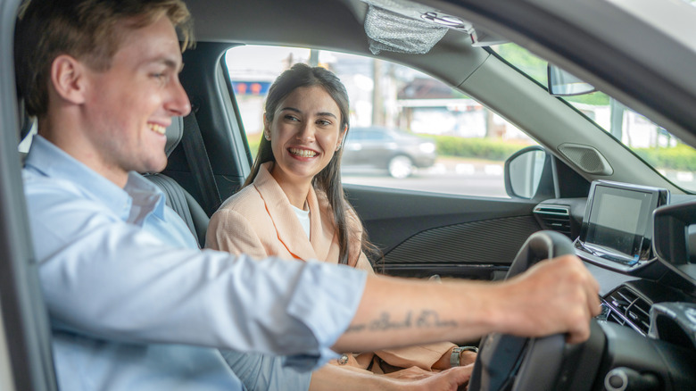 A young happy couple sitting inside the car.