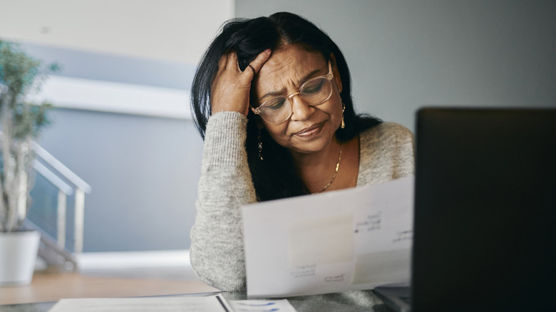 Woman worries while looking at papers