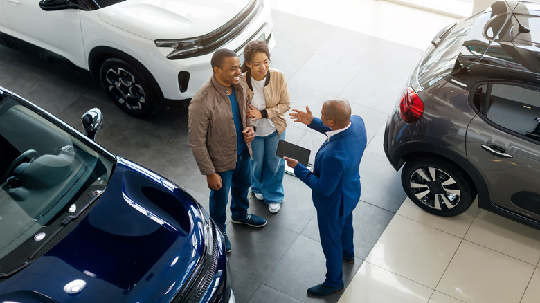 couple talking to a salesperson in a car dealership