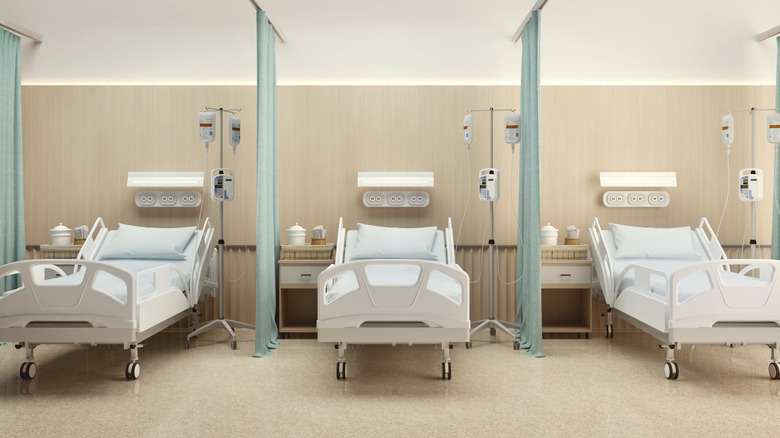 Three empty hospital beds in a hospital bay