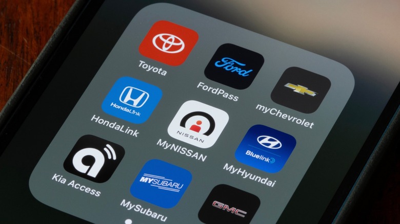 Close-up of a smartphone showing vehicle app icons, including Toyota, FordPass, myChevrolet, and HondaLink