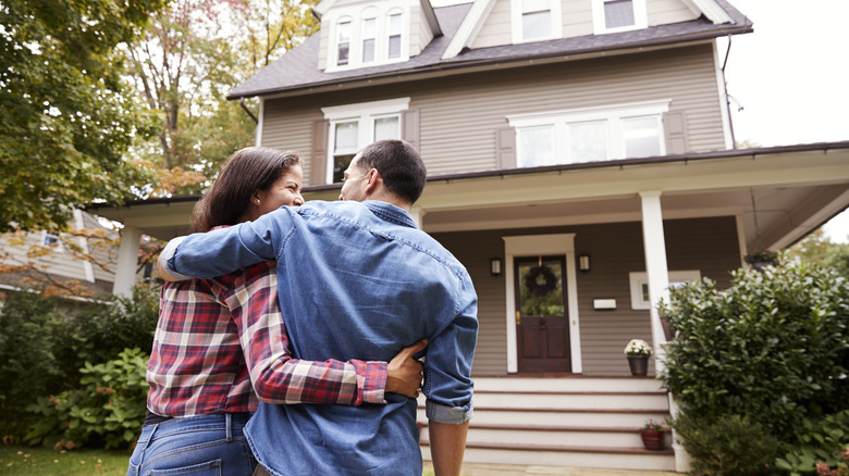 couple embracing while looking at the front of their home