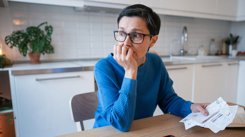 Woman worrying about money, bills in hand