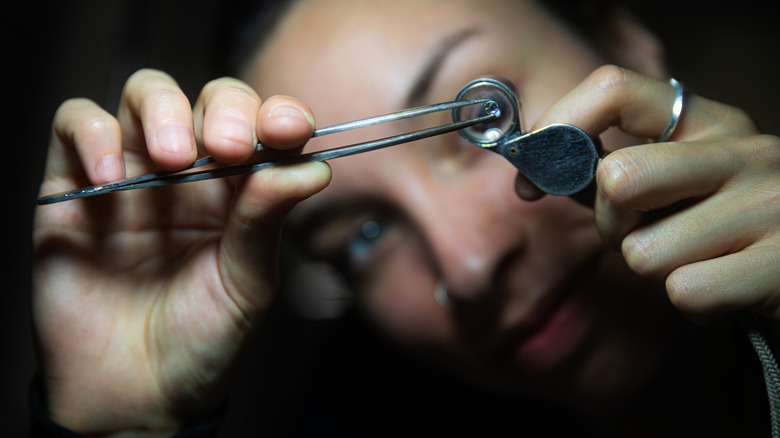 A woman examines a precious stone.