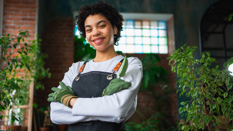 A florist wearing an apron in a botanical store with green plants.