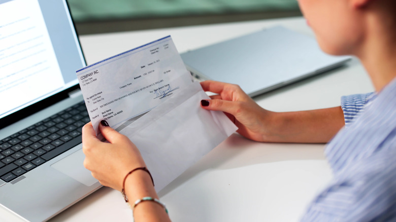 Person looking at a paycheck in front of a computer screen
