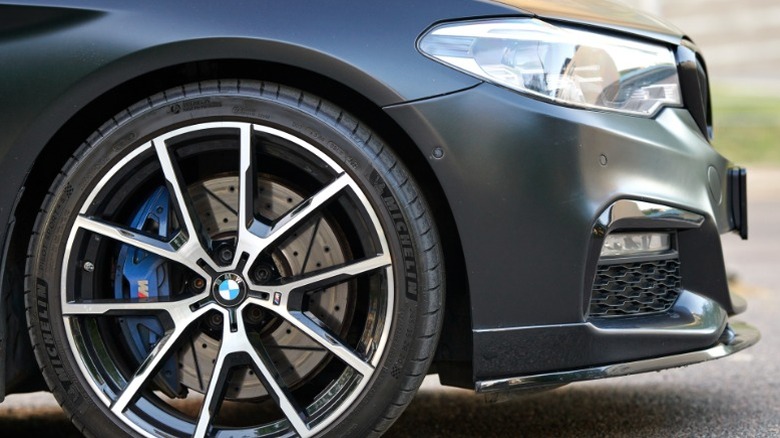 The front passenger-side wheel of a BMW sedan with brake visible through the spokes.
