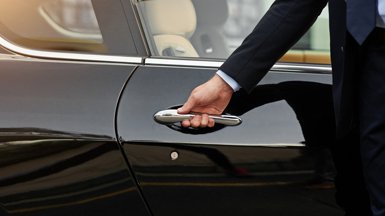 Hand of male person on vehicle handle in professional transport service.