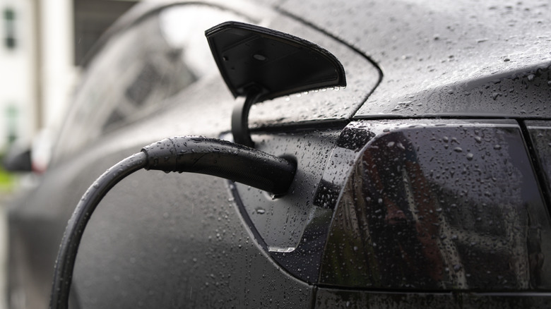 Electric car connected to charging station outside.