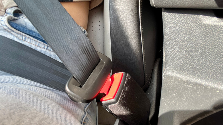 Close-up of a car seatbelt fastened over a person's lap.
