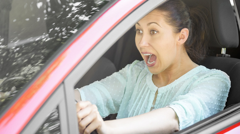 A frightened woman behind the wheel of a moving car.