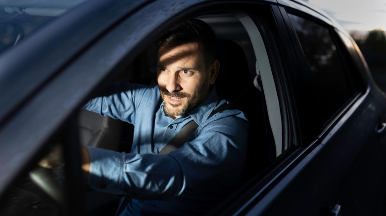 A man driving a vehicle being blinded by bright high beams from another vehicle.
