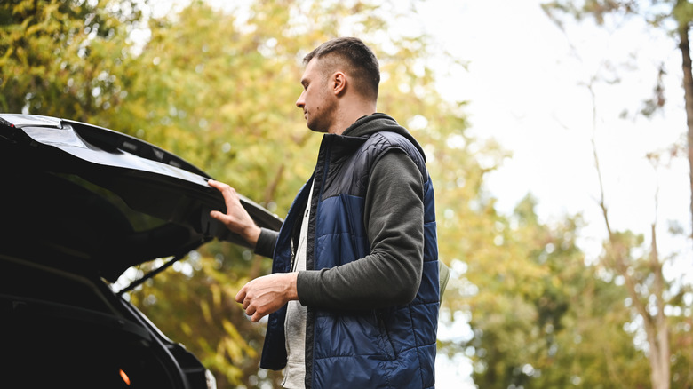 A man with a serious expression standing in front of his open tailgate.