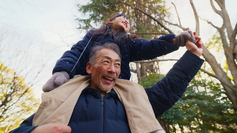 A senior carrying a child on shoulders